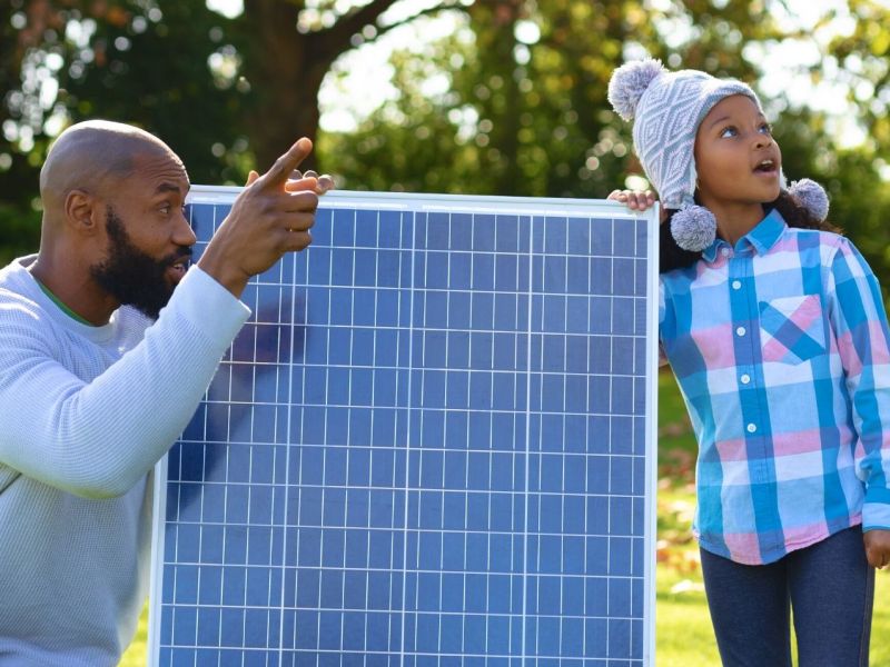 Mann zeigt seiner Tochter eine kleine Solaranlage