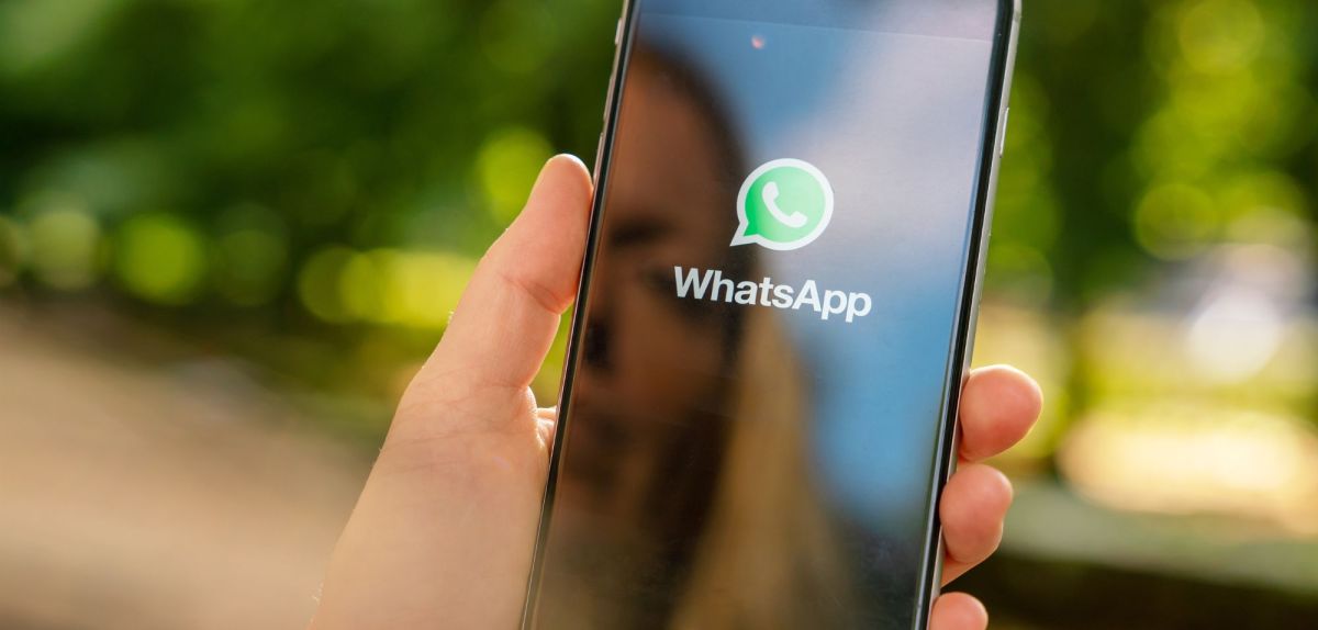 WhatsApp auf dem Handy, im Hintergrund ein Park