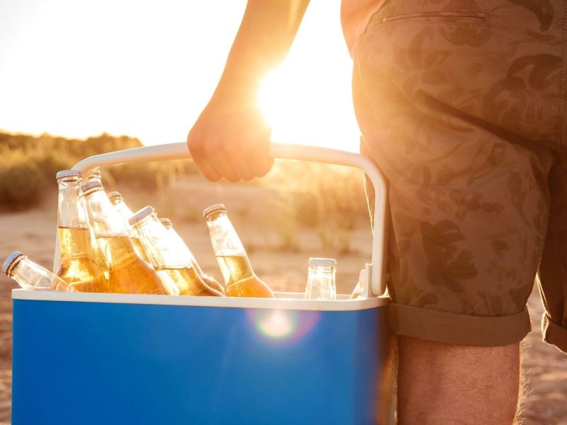 Mann mit Kühlbox am Strand