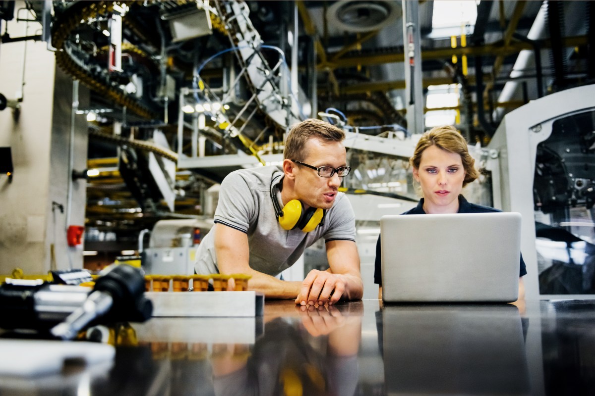 Mann und Frau in einem technischen Beruf. Sie schauen auf einen Laptop.