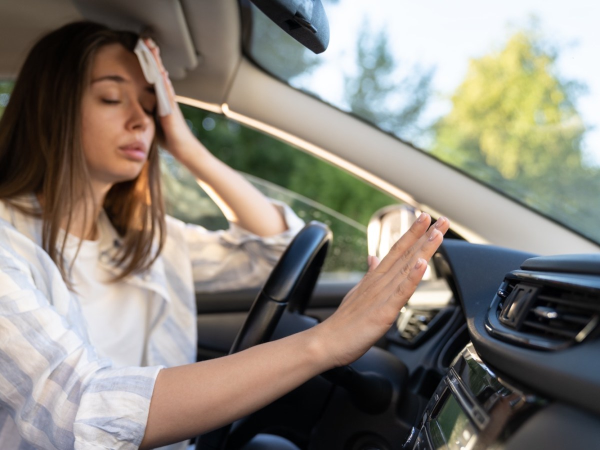 Frau hÃ¤lt im Auto die Hand vor die Klimaanlage