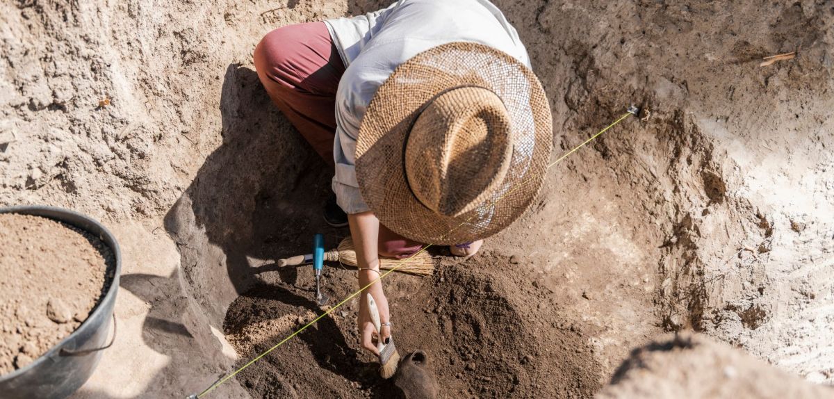 Person bei einer archÃ¤ologischen Ausgrabung.