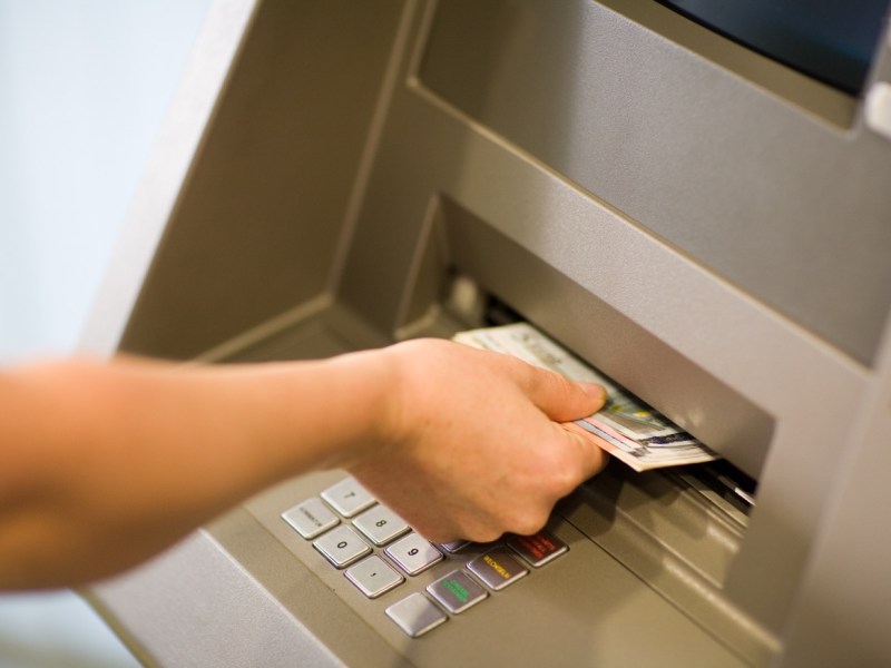 Person hebt Geld am Automaten ab