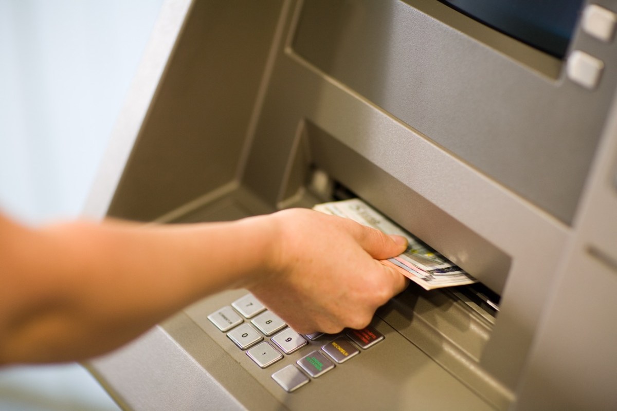 Person hebt Geld am Automaten ab