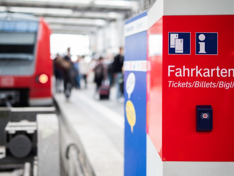 Hinweis auf Tickets am Bahnhof mit Zug im Hintergrund