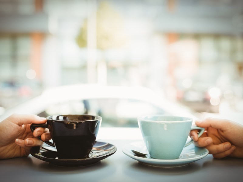 Zwei Menschen mit Tassen voll Kaffee