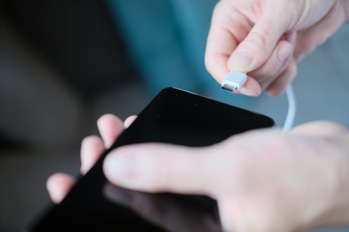 Person schlieÃŸt Ladekabel an ein Smartphone an.