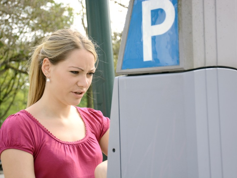 Junge Frau hat Probleme am Parkscheinautomaten