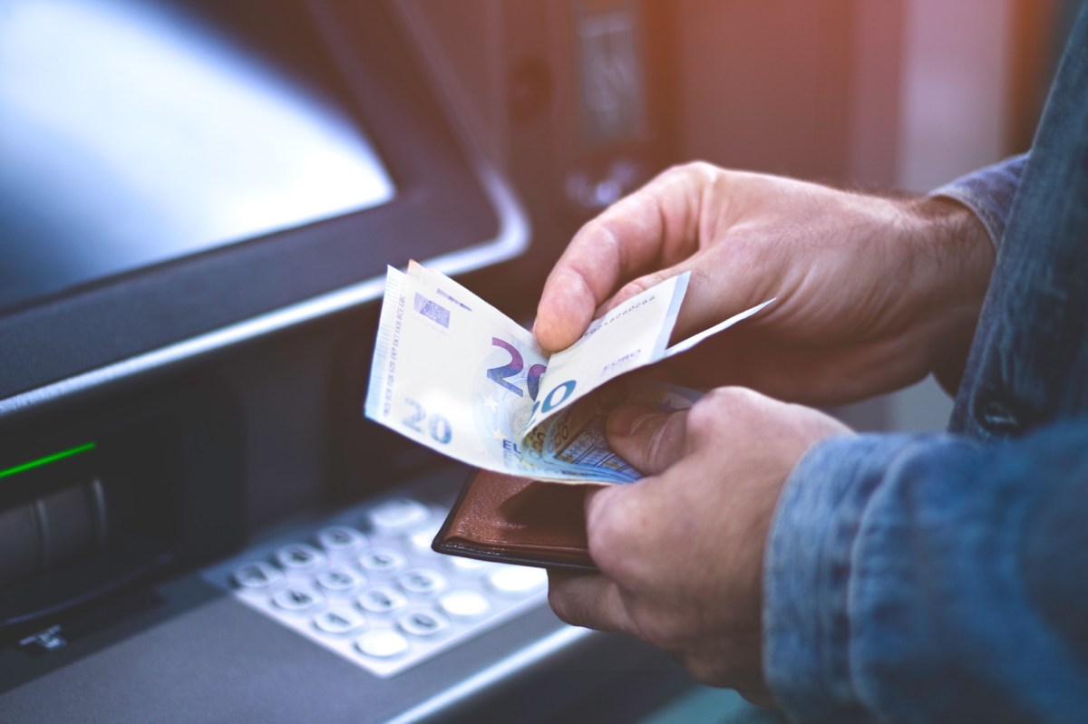 Mann hebt Geld am Automaten ab
