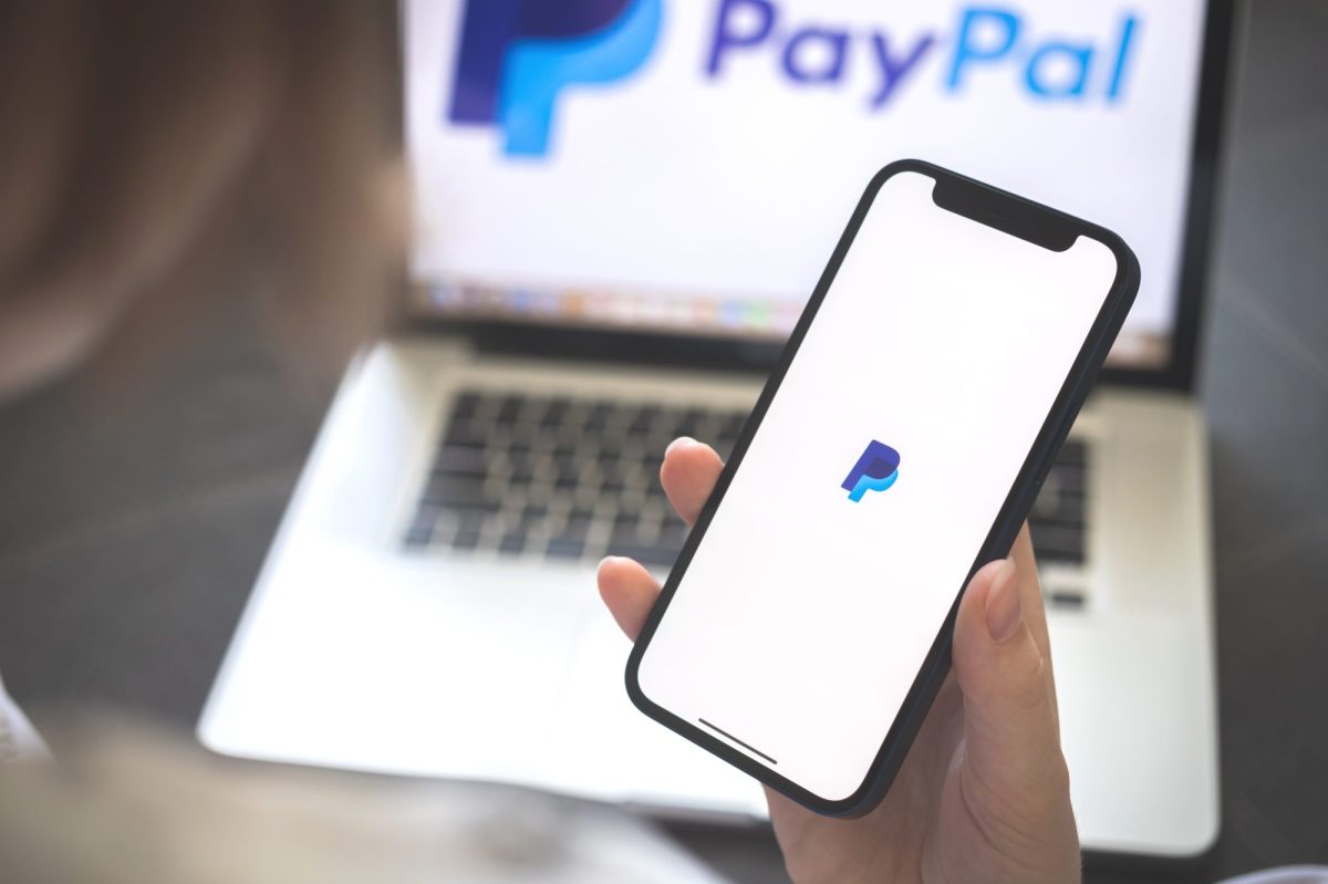 Eine Person nutzt PayPal auf Laptop und Smartphone.