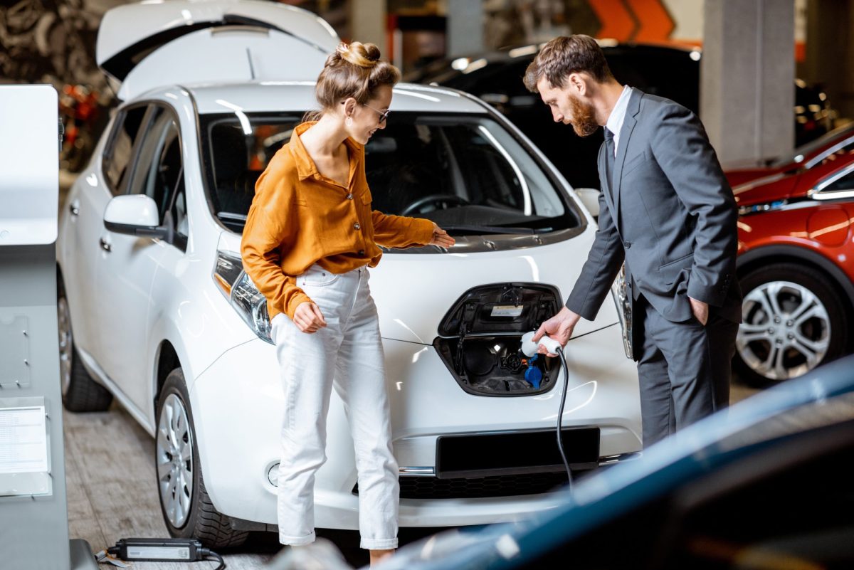 Ein Händler führt seiner Kundin ein neues Elektroauto vor.