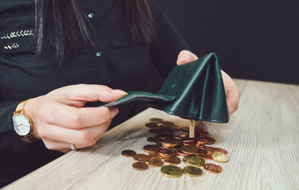 Person schüttet Münzen aus einem Portemonnaie.