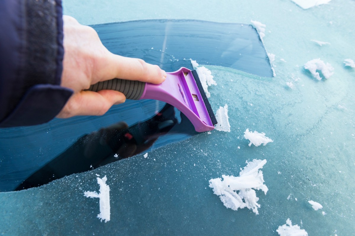 Person kratzt eine Autoscheibe frei