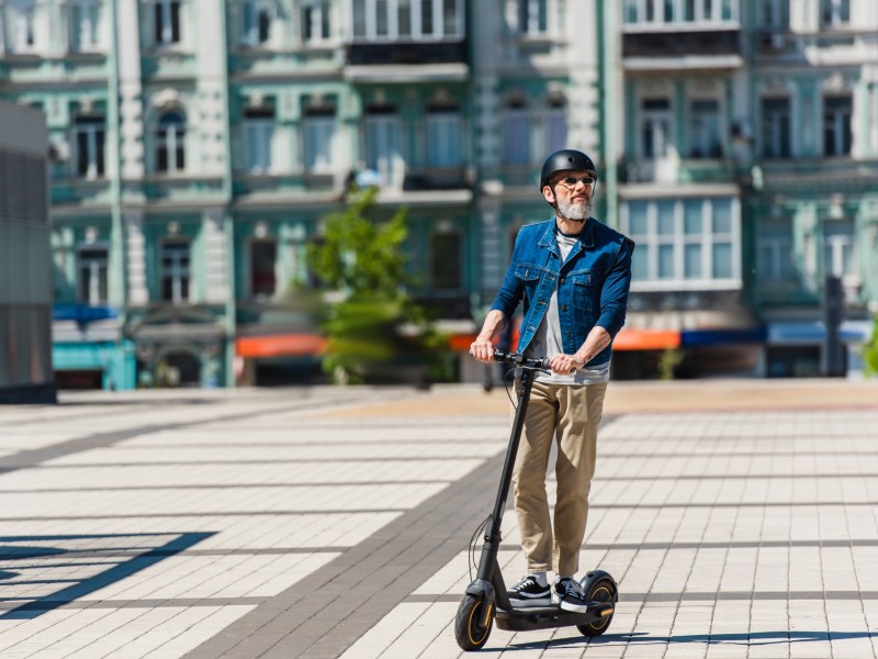 Mann auf einem E-Scooter in der Stadt.