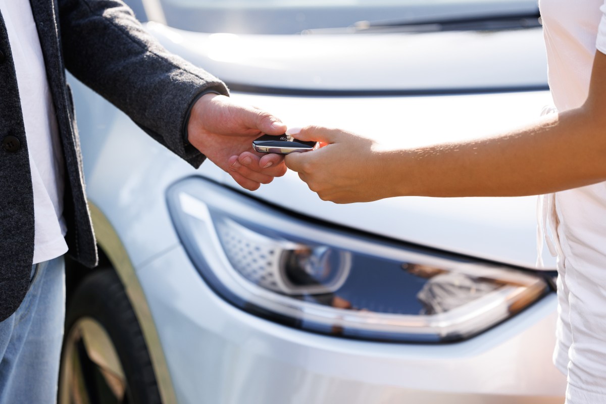 Person übergibt den Schlüssel eines Elektroautos