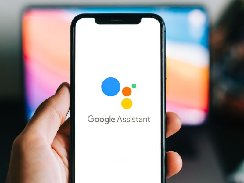 Person hält Handy mit Google Assistant in der Hand.