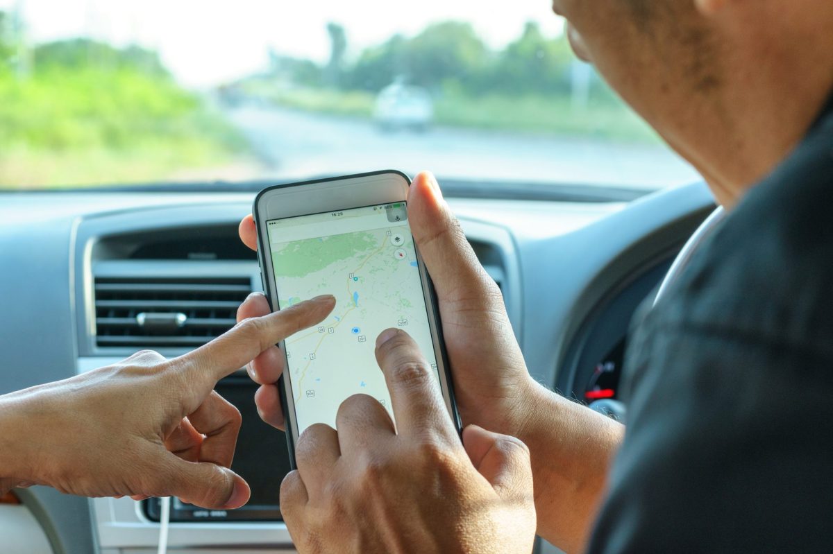 Mann und Frau deuten in Auto auf Google Maps auf dem Handy.