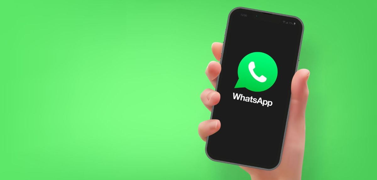 Person hält Handy mit dem WhatsApp-Logo in der Hand.