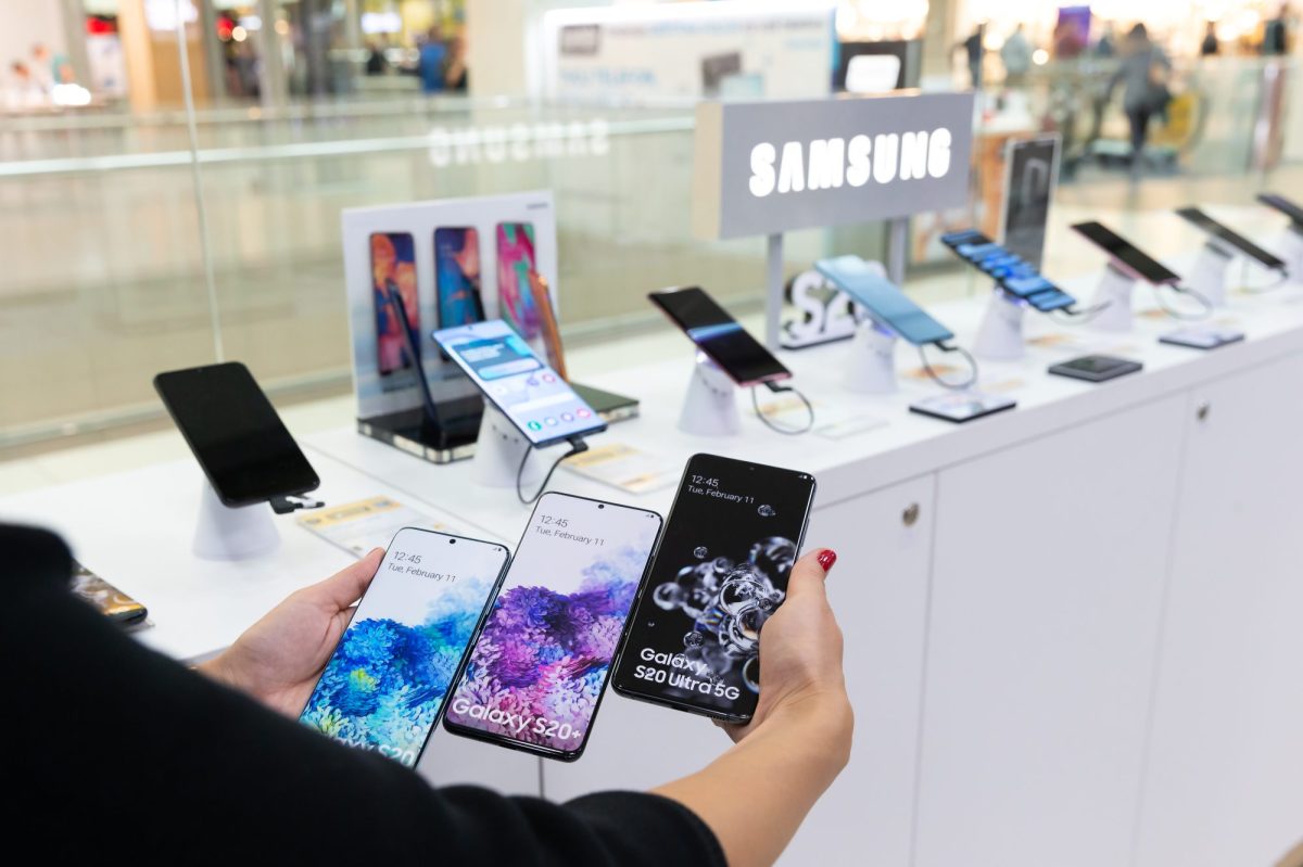 Person hält mehrere Samsung-Handys nebeneinander in einem Laden.