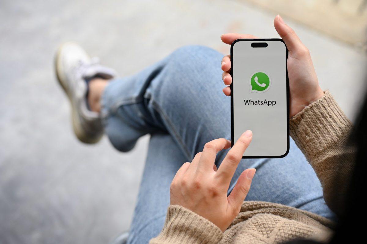 Frau hält ein Smartphone, auf dem WhatsApp geöffnet ist.