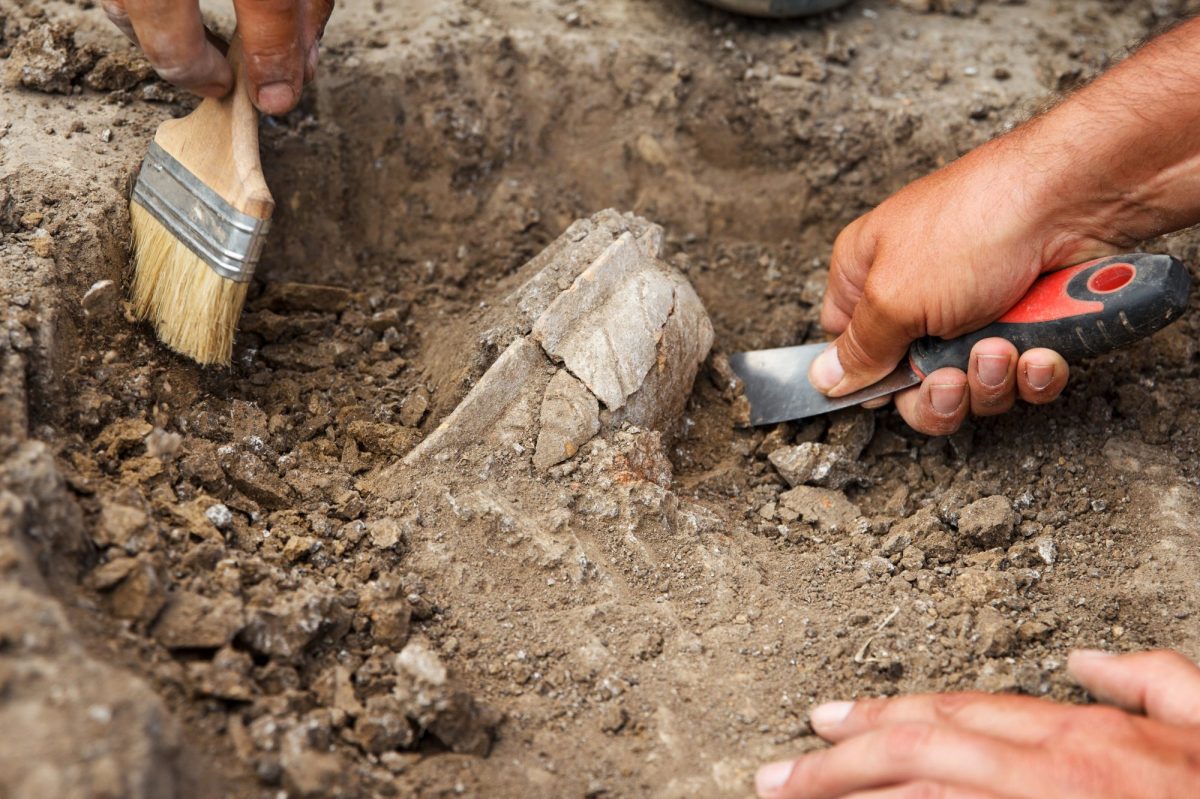 HÃ¤nde graben mit Werkzeugen an archÃ¤ologischem Fund.