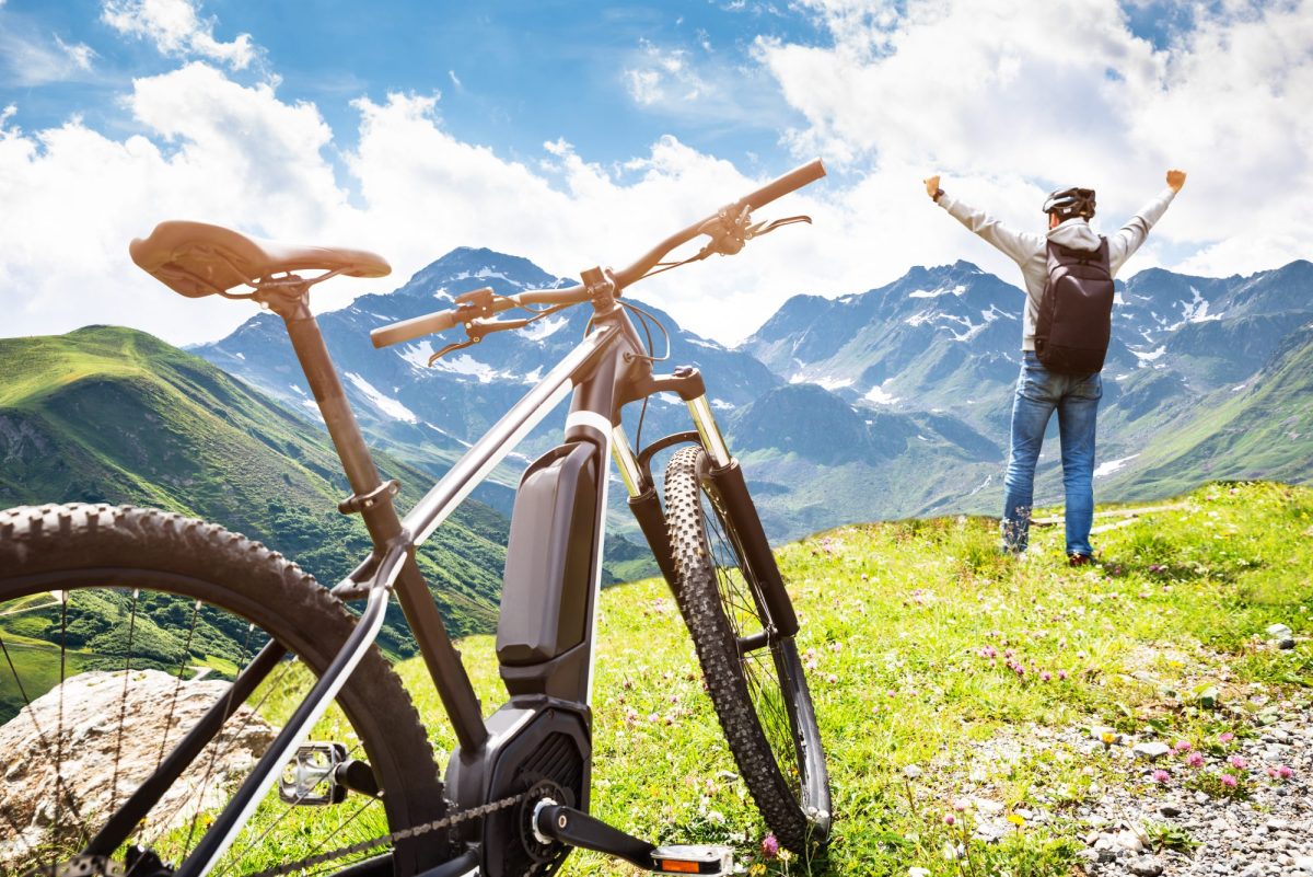 E-Bike auf einer Wiese, mit Mann daneben.