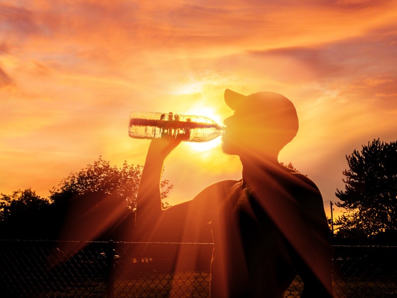 Mann trinkt Wasser vor Sonnenuntergang