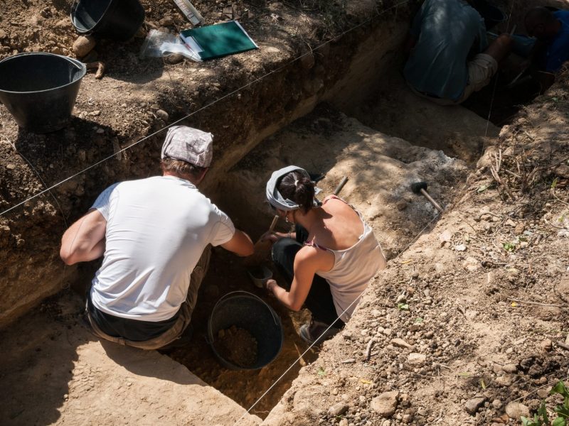 Zwei Archäolog*innen graben an einem archäologischen Fund.