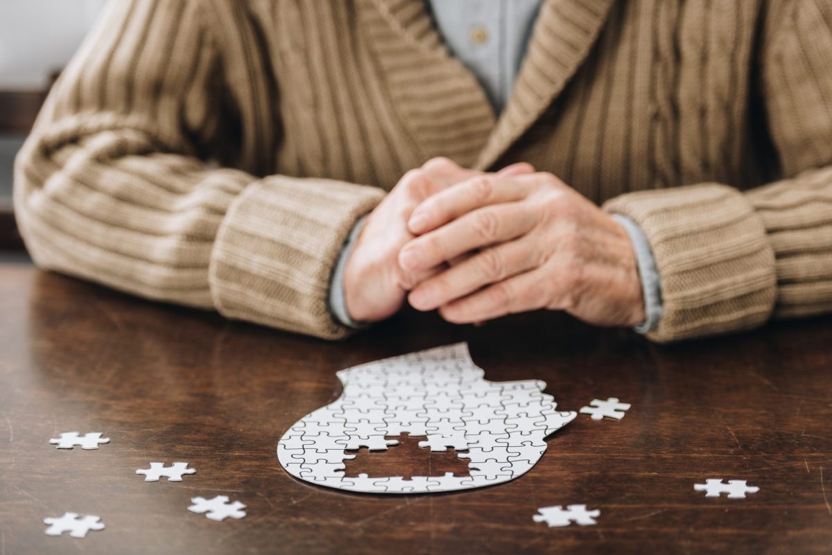 Ã„ltere Mann puzzelt an einem Tisch.