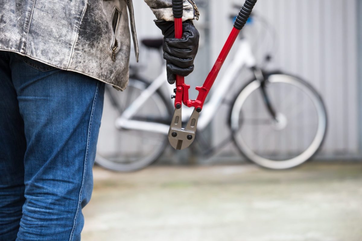 Person hält eine Zange. Im Hintergrund steht ein Fahrrad an einer Wand.