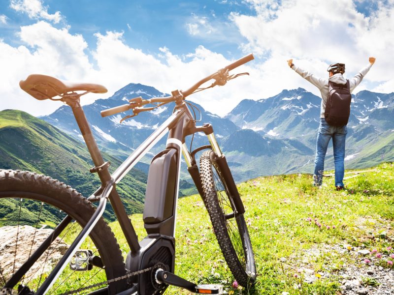 Mann steht neben E-Bike auf einem Berg.