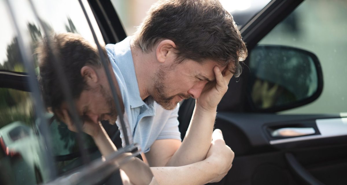 Mann sitzt aufgelÃ¶st auf dem Beifahrersitz eines Autos