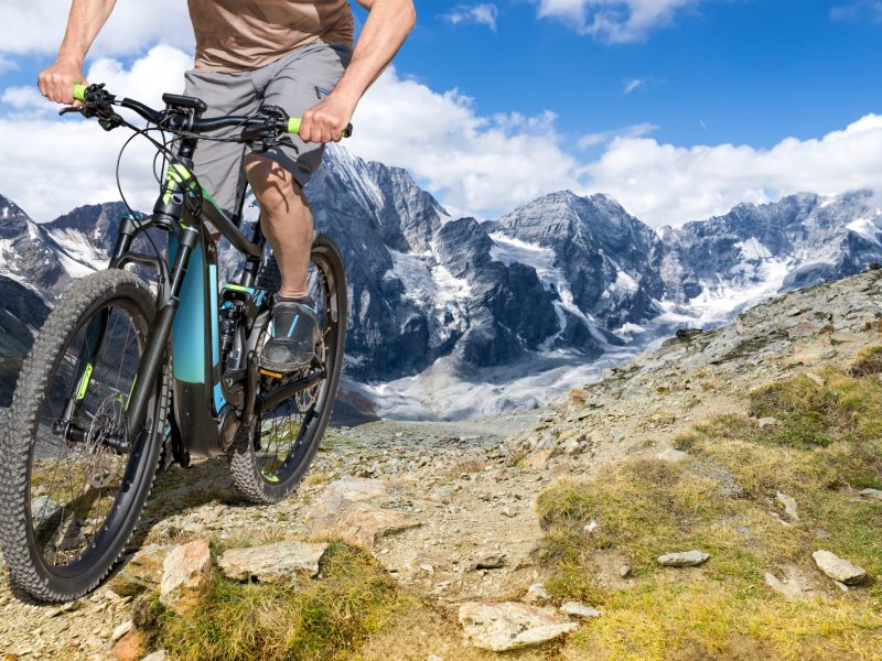 Mann auf einem E-Bike auf einem Bergpfad.