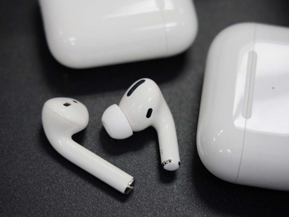 Zwei AirPods-Kopfhörer liegen neben der Hülle auf einem Schwarzen Hintergrund.