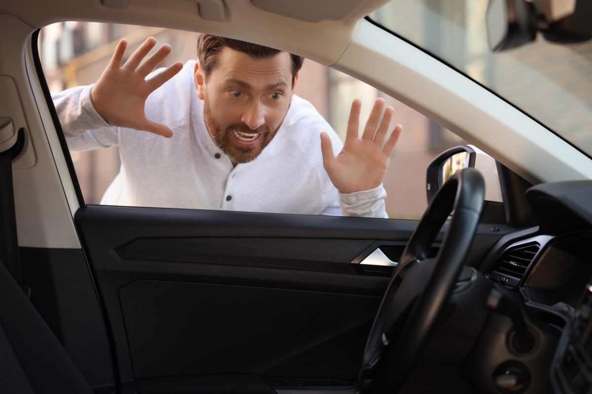 Ein blickt erschrocken durch die Scheibe eines Autos. Im Innenraum steckt der AutoschlÃ¼ssel.