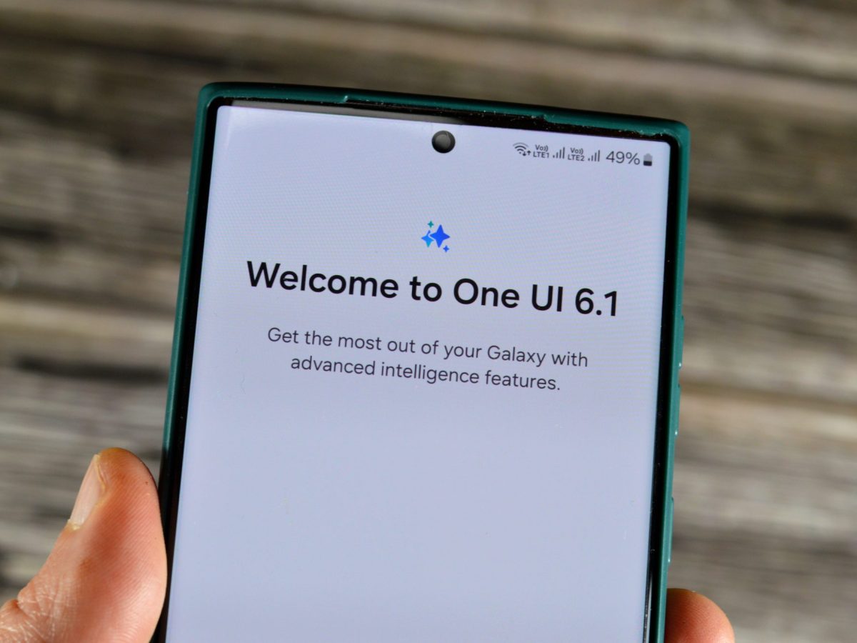 Person hält ein Samsung Galaxy in der Hand. Auf dem Display steht "Welcome to One UI 6.1"