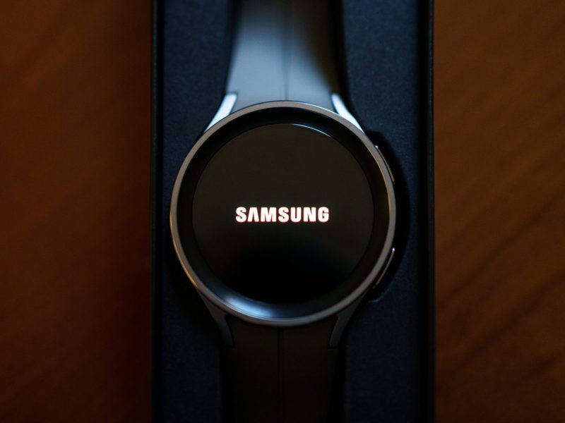 Eine Samsung Galaxy Watch5 liegt auf einem dunklen Hintergrund. Auf dem Display steht "Samsung" geschrieben.