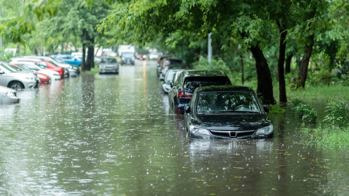 Überschwemmung auf einer Straße mit parkenden Autos. (