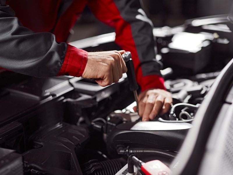 Mann arbeitet mit Werkzeug am Motor im Auto.