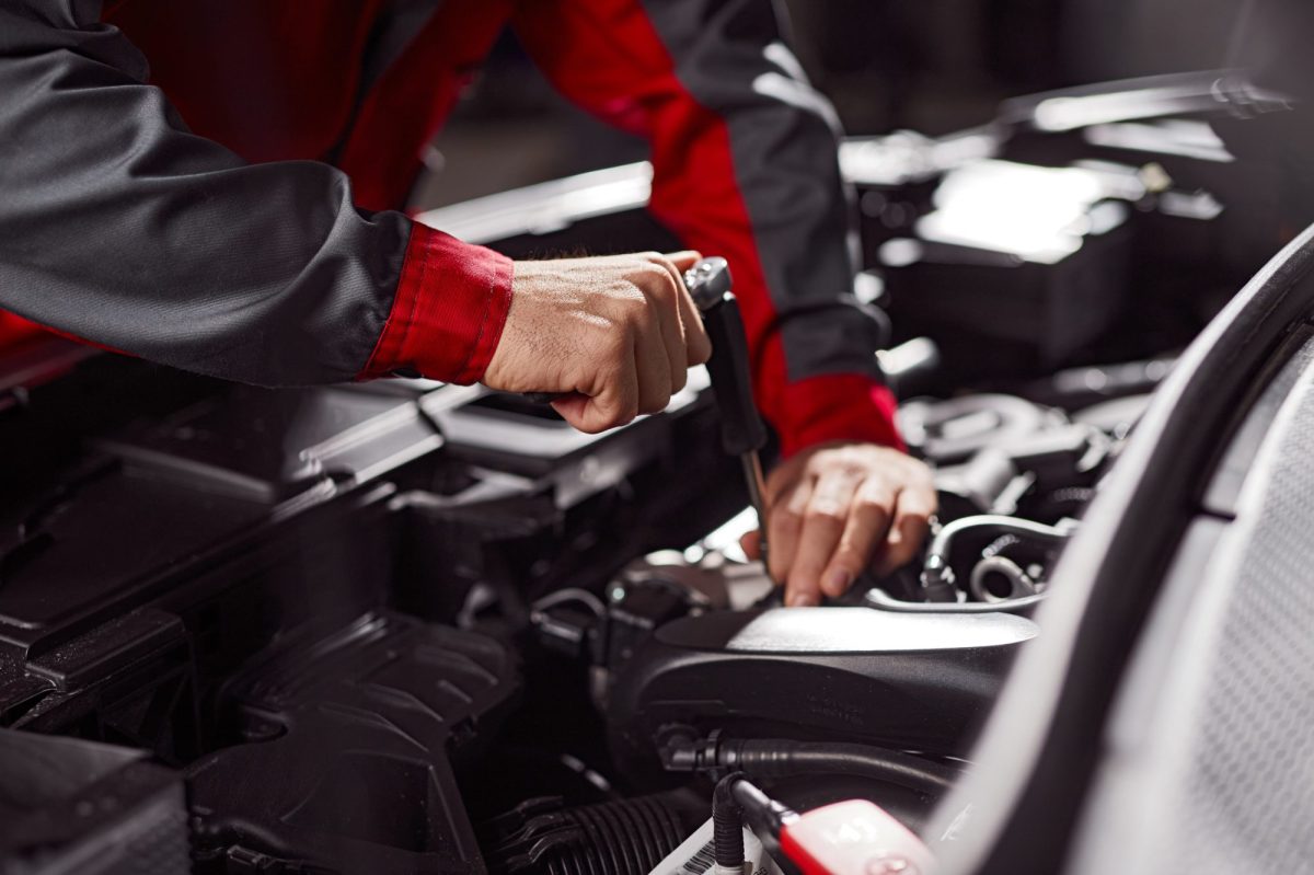 Mann arbeitet mit Werkzeug am Motor im Auto.