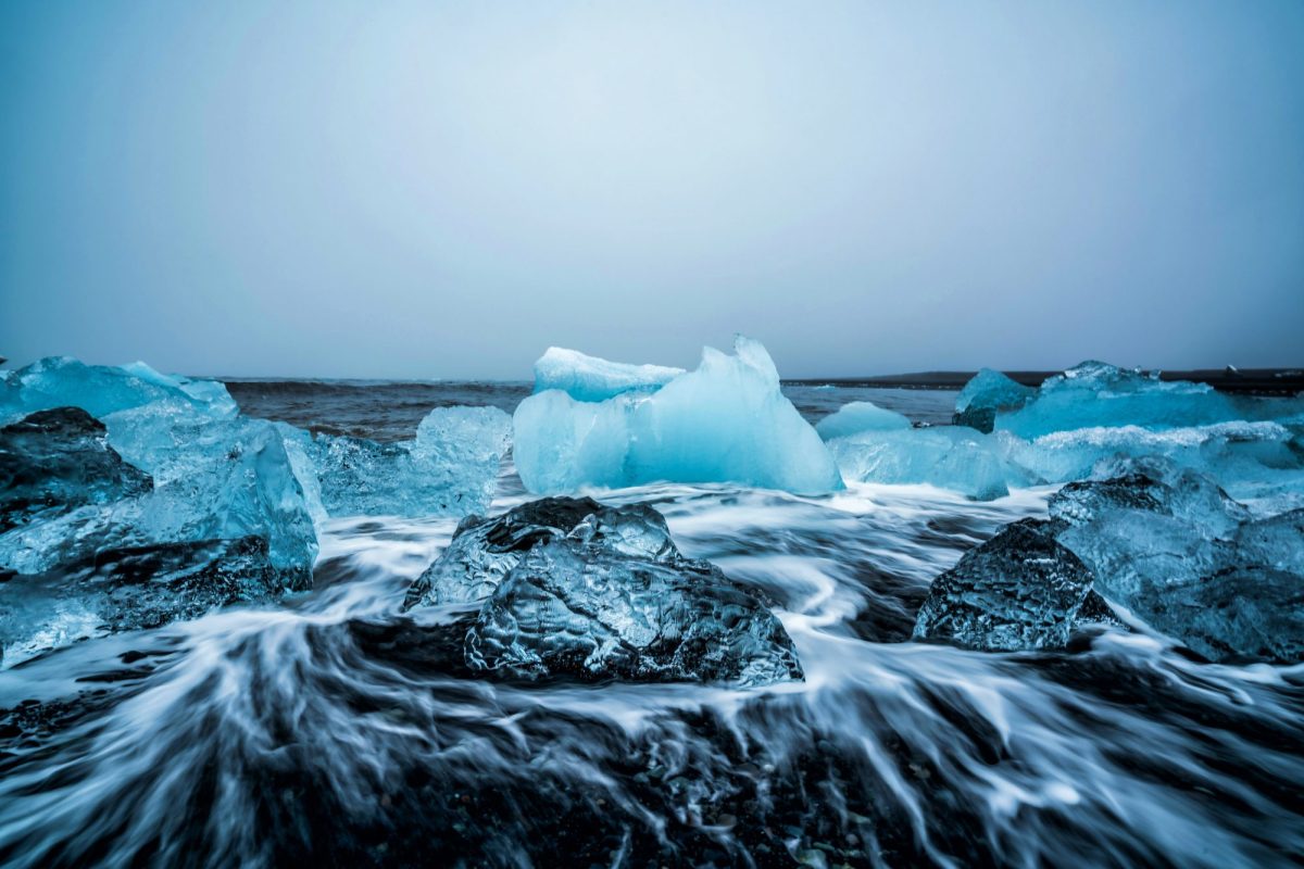 Eisformationen auf dunklem Stein vor einem weiÃŸen Himmel.