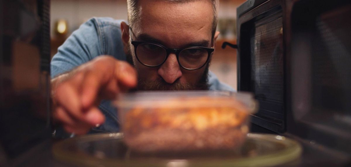 Mann stellt Essen in Mini-Mikrowelle