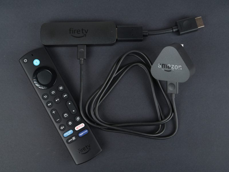 Amazon Fire TV Stick und Fernbedienung liegen auf einem dunklem Untergrund.