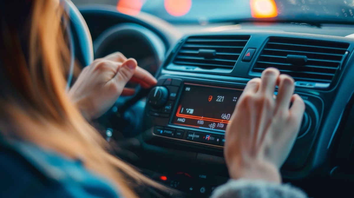 Frau stellt mehrere Knöpfe im Auto ein.