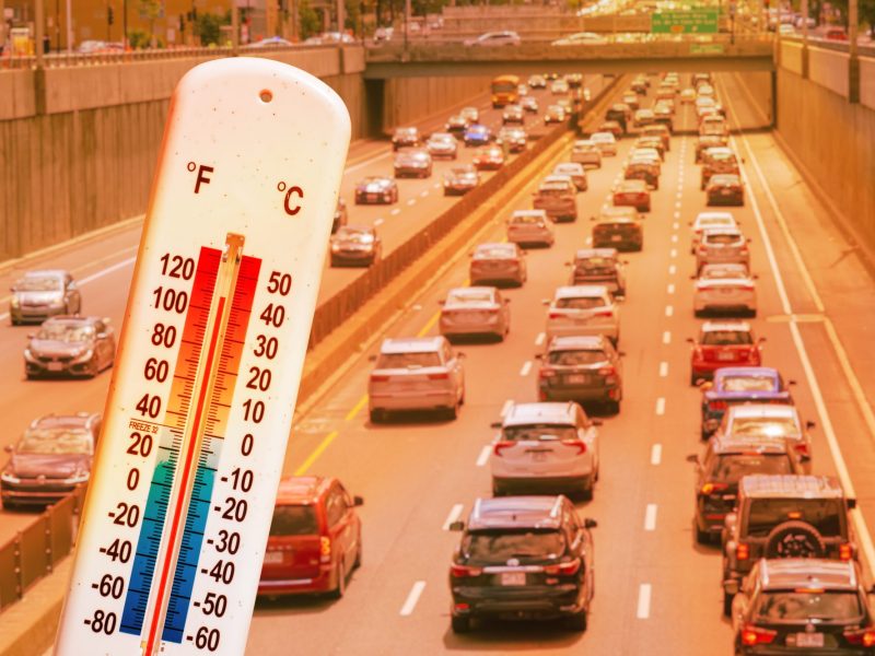 Autos fahren auf einer dreispurigen Autobahn. Im Vordergrund ist ein Thermometer zu sehen.