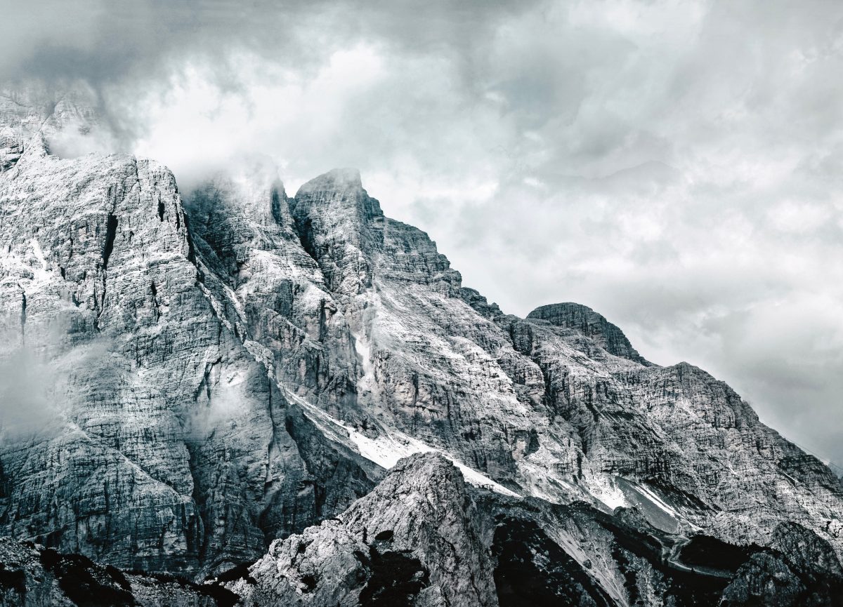 Von Schnee bedeckte Berglandschafr, die von Nebel umgeben ist.