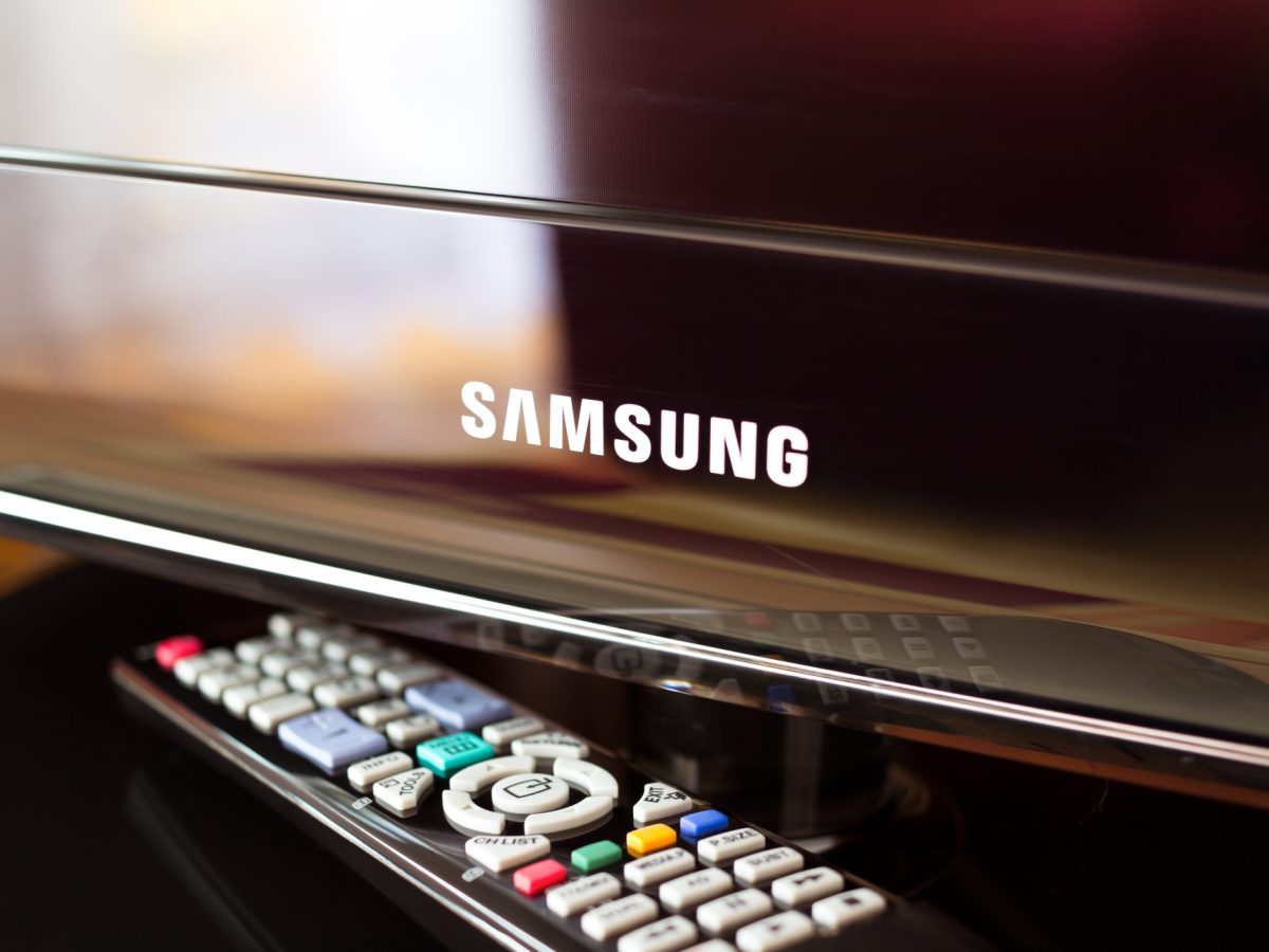 Eine Fernbedienung liegt neben einem Samsung-Fernseher.
