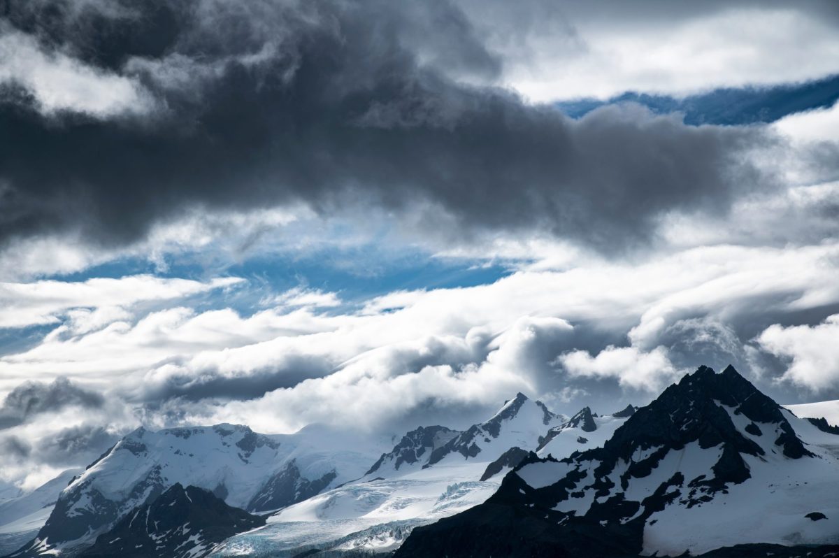 Wolken über schneebedeckten Bergen.