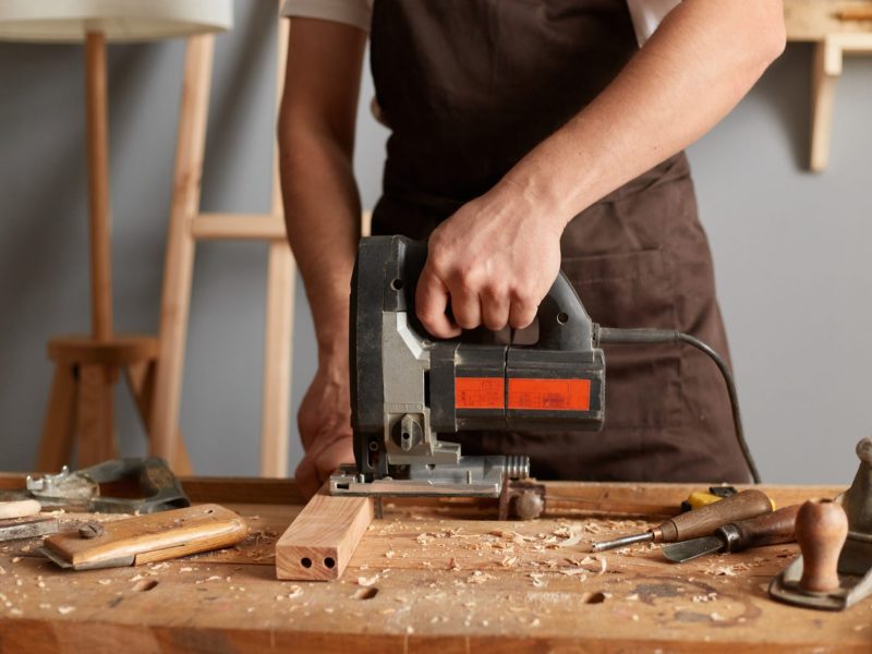 Person bearbeitet Holz mit einer Stichsäge