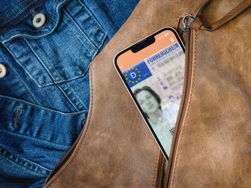 Führerschein auf einem Handy, das in einer Jackentasche steckt.